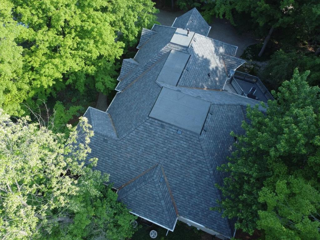 Aerial drone view of completed residential roof surrounded by trees