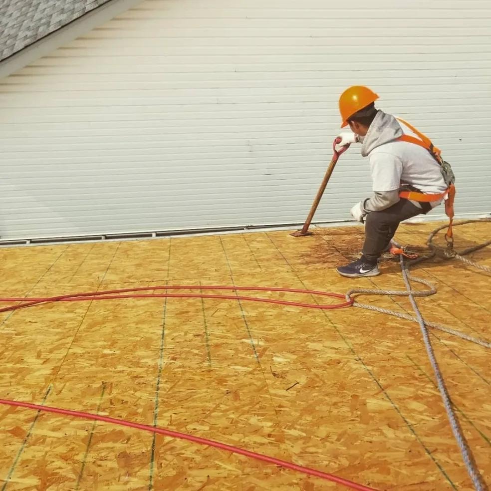 Roofer working on roof deck with safety harness